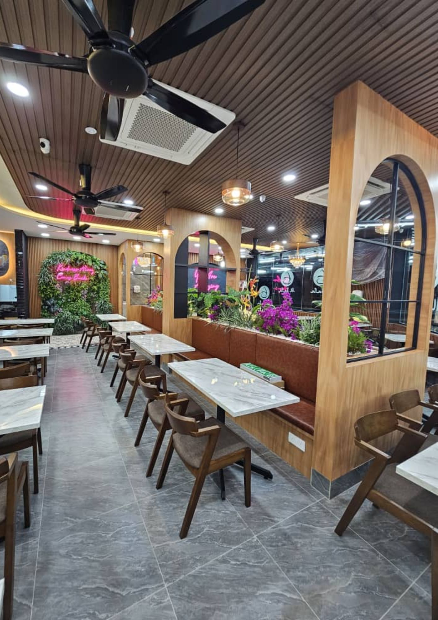 Al-Safa Mamak Café interior with arched timber booth dividers, marble tables and lush greenery in Johor Bahru