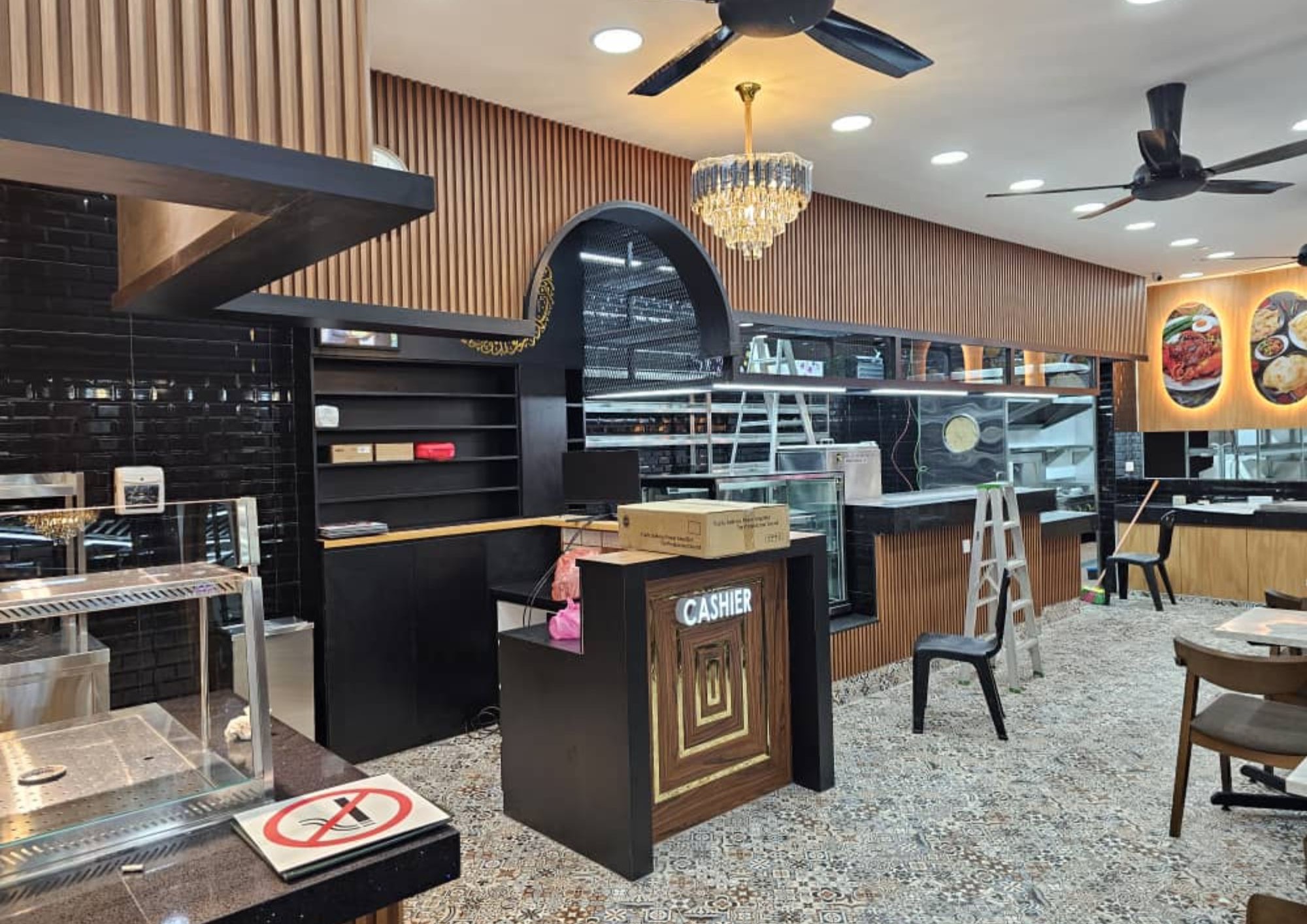 Cashier counter with black tile feature wall, glass display case and pendant chandelier