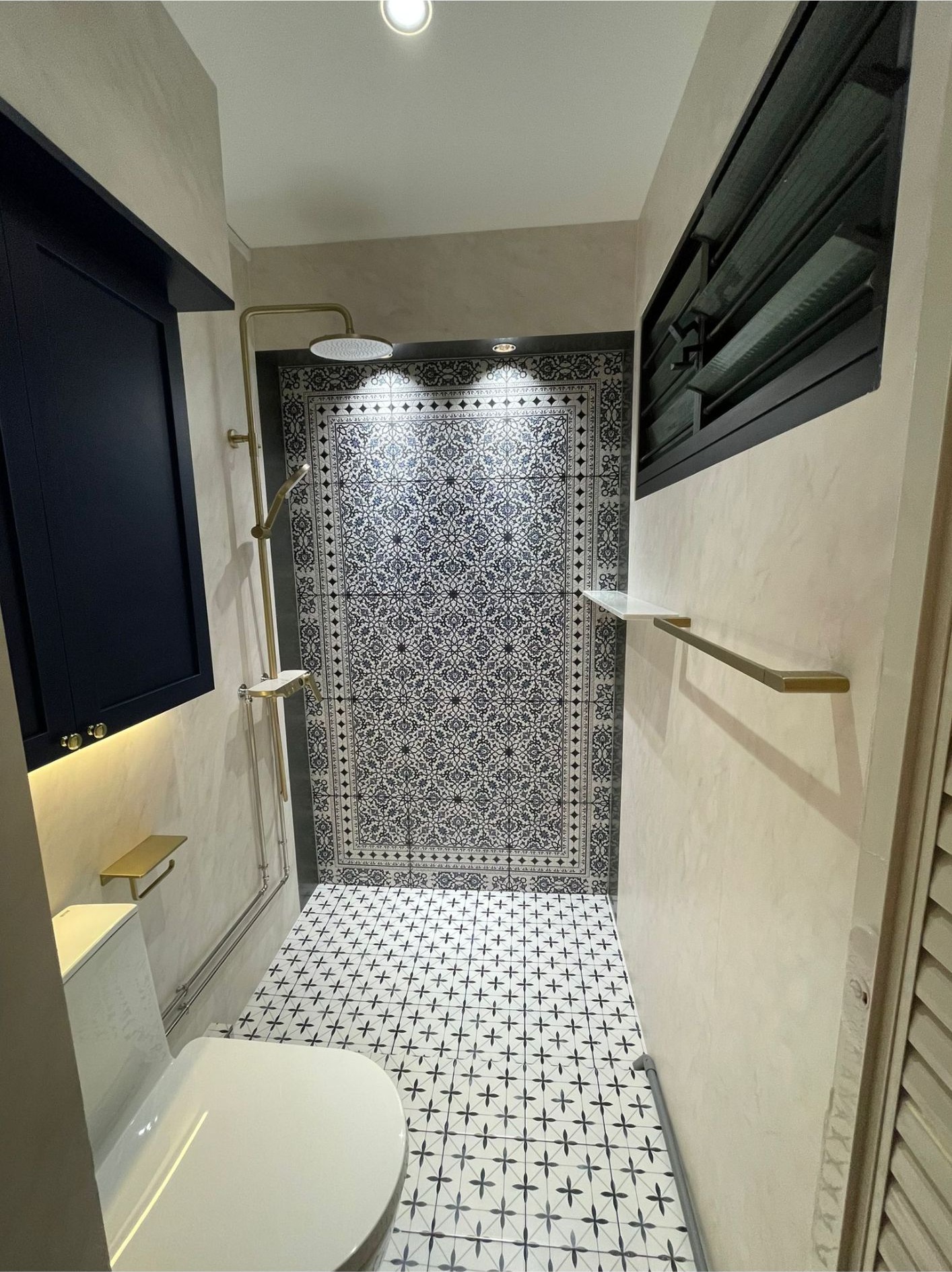 Bathroom with Peranakan-style patterned tiles, star-cross floor, navy vanity and brass fixtures