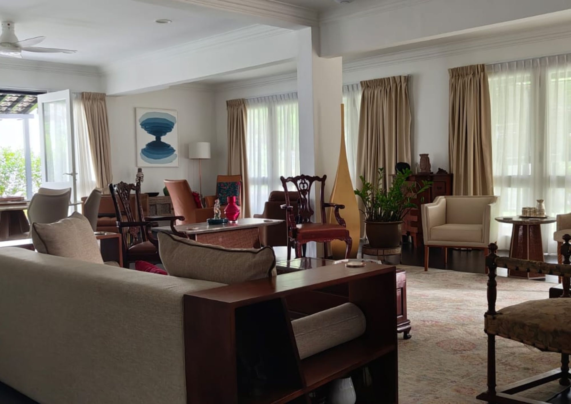 Wide living room with heritage furniture, beige curtains, art pieces and natural light