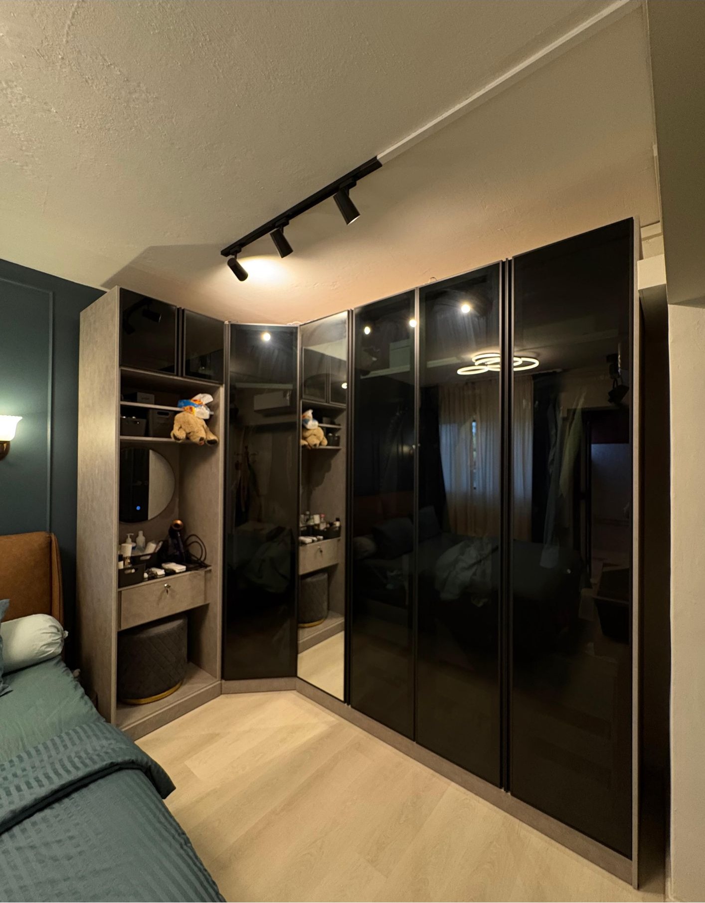 Glossy black L-shaped built-in wardrobe with open shelving and track lighting