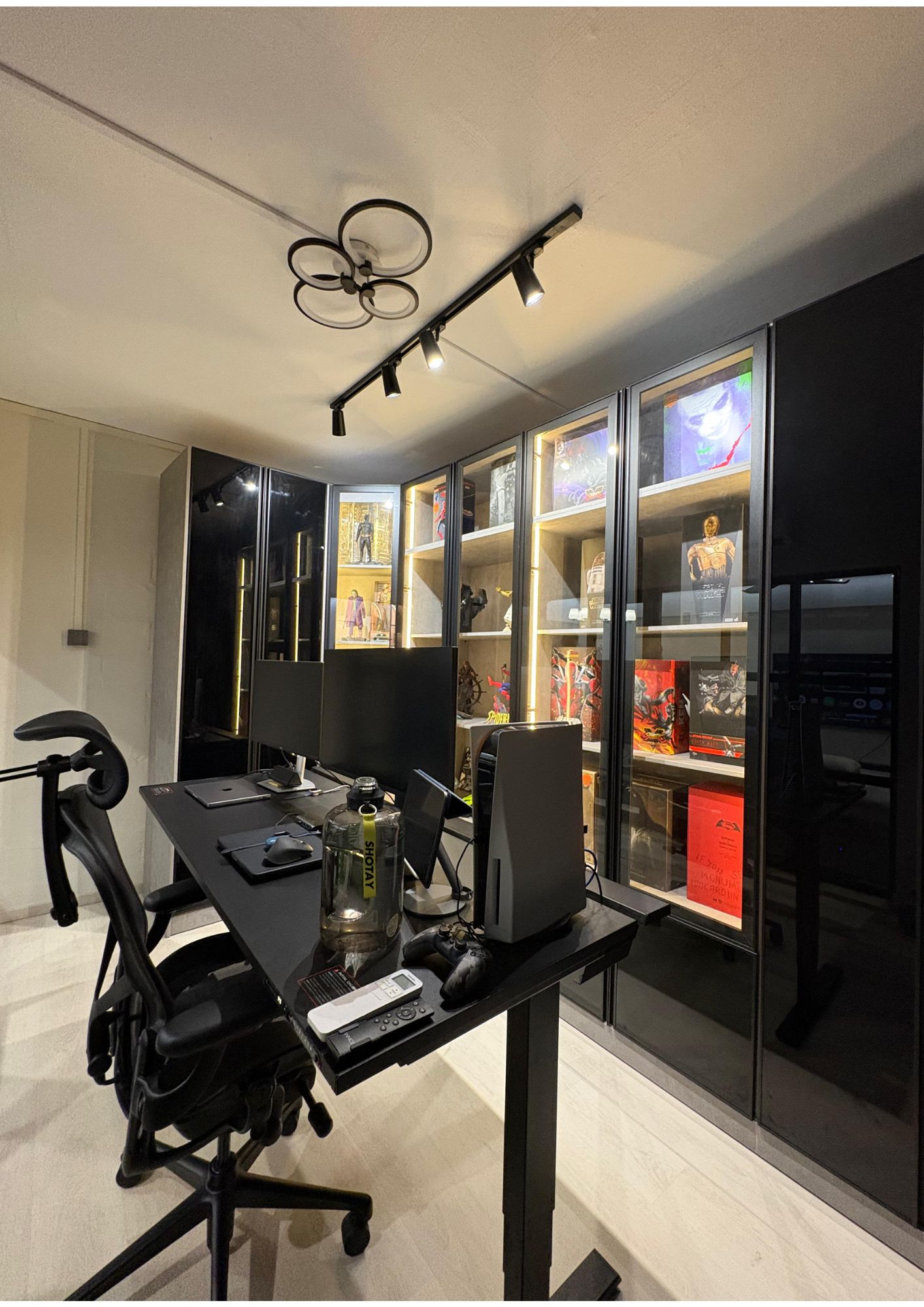 Study room with black desk, gaming chair and LED-lit glass display cabinets for figurine collection