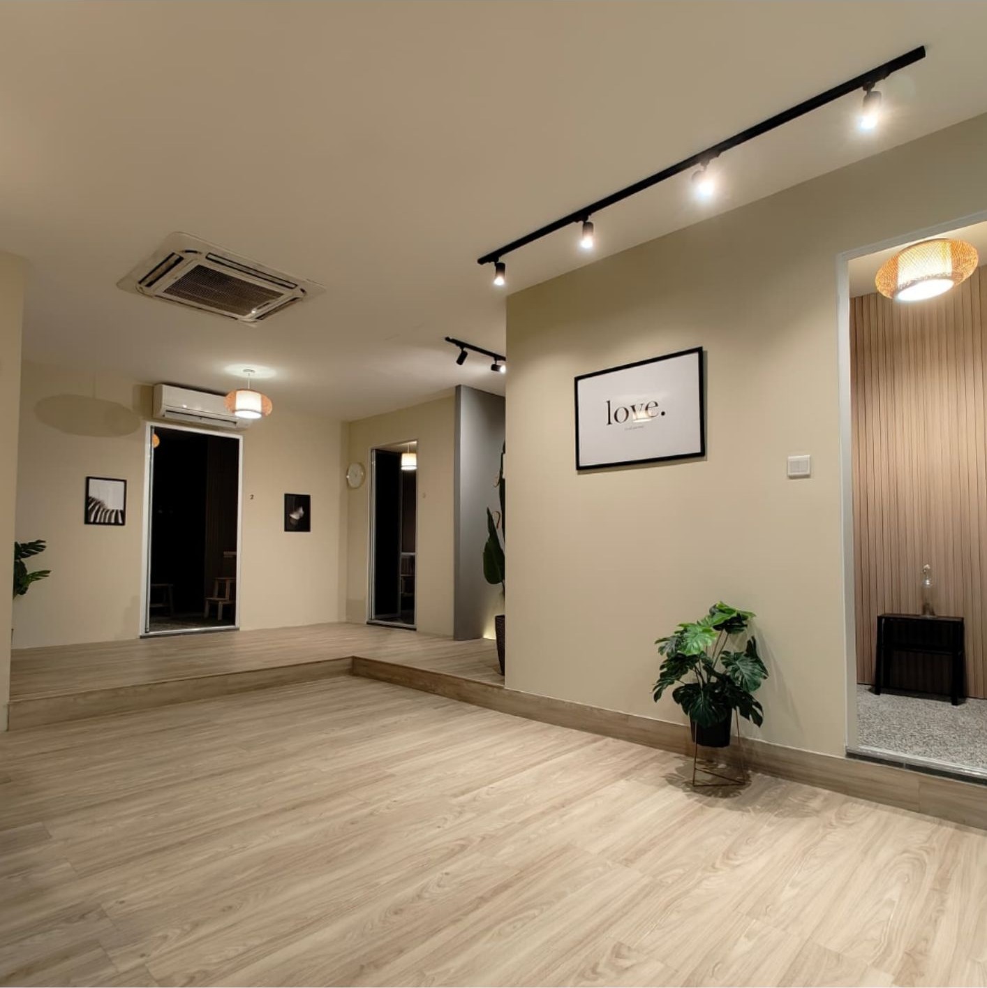 Open wellness area with track lighting, 'love' print, monstera plant and timber-slat wall detail