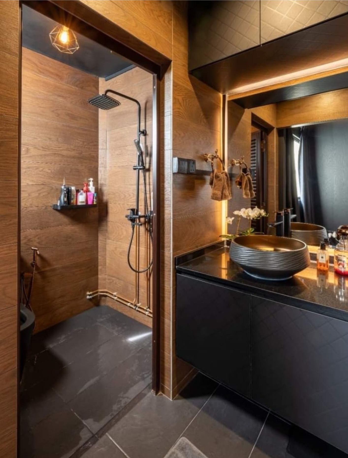 Bathroom with timber-look wall tiles, black rain shower, stone vessel basin and industrial pendant