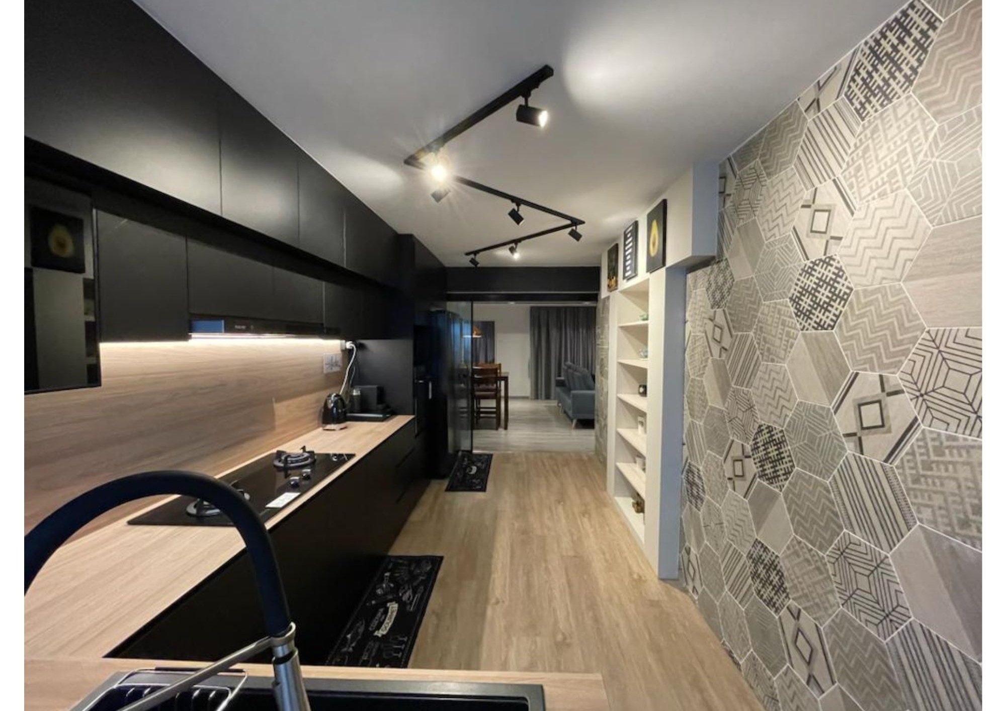 Kitchen with geometric patterned floor tiles, light wood upper cabinets and industrial wall lamp