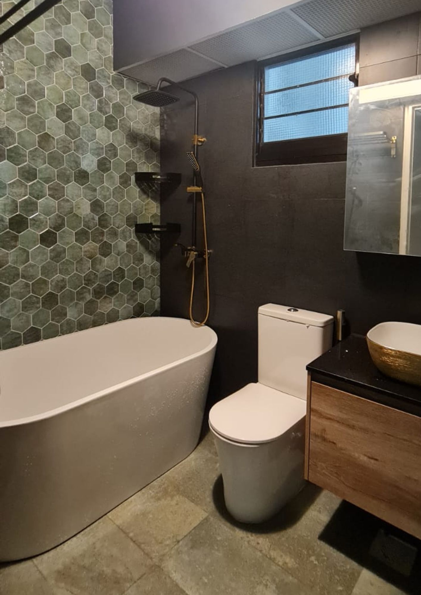 Master bathroom with green hexagonal tile feature wall, freestanding bathtub and gold fixtures